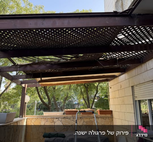 פרגולת עץ במרפסת עם סבכה שבורה וסולם המיועד לתיקון